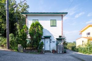 a white house with a blue door on a street at Villent Ito Kawana - Vacation STAY 91110v in Ito