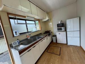 a small kitchen with a sink and a refrigerator at みんぱく明治村 in Tome