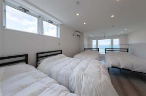 a bedroom with three beds with white sheets at Tabinoteitaku Y-beach - Vacation STAY 91093v in Tsuruoka