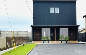 a black building with potted plants in front of it at Tabinoteitaku Y-beach - Vacation STAY 91093v in Tsuruoka