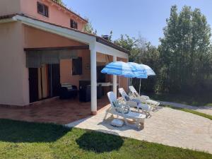 a group of chairs and umbrellas next to a house at Charming Pool Home Near Pula in Pula