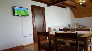 a dining room with a table and a television on a wall at Apartment Nina in Drežnik Grad