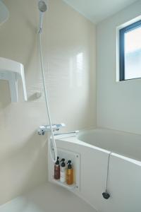 a white bathroom with a shower with bottles on a shelf at Green Peak - Vacation STAY 05851v in Minami Aso