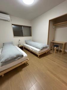 a bedroom with two beds and a table and a window at OUCHI Oaramachi - Vacation STAY 18642 in Goto