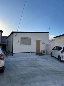 a white building with two cars parked in a parking lot at OUCHI Oaramachi - Vacation STAY 18642 in Goto