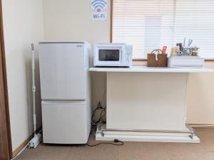 a kitchen with a refrigerator and a microwave on a counter at Minpaku ROADHOUSE - Vacation STAY 20160v in Nagasaki