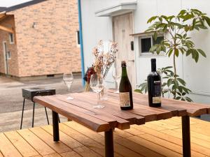 einem Holztisch mit zwei Flaschen und Gläsern darauf in der Unterkunft Hyuga Surf Camp 105 - Vacation STAY 29665v in Hyuga