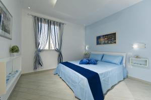 a bedroom with a bed with blue sheets and a window at Case Della Baia in Castellammare del Golfo