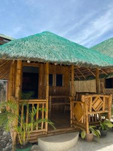 a wooden hut with a deck with a grass roof at Moalboal Beach Front Hotel in Moalboal