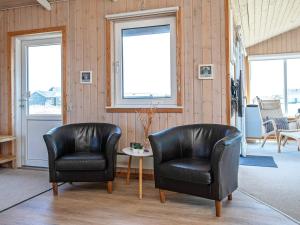 two leather chairs and a table in a room with windows at 4 star holiday home in Lemvig in Ferring