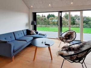 a living room with a blue couch and a dog sitting in chairs at 6 person holiday home in Slagelse in Slagelse