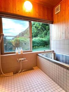 a bathroom with a bath tub and a window at Gubo Satoyama Suite Lodge & Camp - Vacation STAY 39503v in Katsuura
