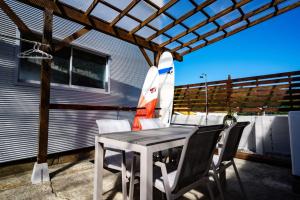 une table et des chaises sur une terrasse avec une planche de surf dans l'établissement Hyuga Surf Camp202 - Vacation STAY 31884v, à Hyuga