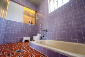 La salle de bains est pourvue de carrelage bleu, d'une baignoire et de toilettes. dans l'établissement Hyuga Surf Camp202 - Vacation STAY 31884v, à Hyuga