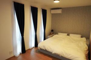 a bedroom with a white bed and two windows at Hikarinoyado Yamate - Vacation STAY 18639 in Sasebo