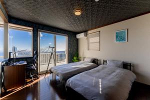 une chambre avec deux lits et un bureau et une fenêtre dans l'établissement AZUR Izu Atagawa aurora - Vacation STAY 31844v, à Okawa