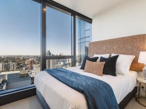 a bedroom with a large bed and large windows at Matilda's Skyview - Luxe 2BR, 2BA Near Crown in Melbourne +10 photos