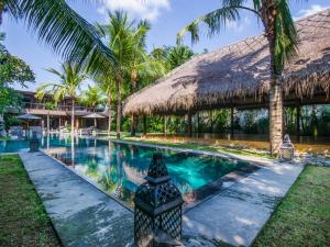 a swimming pool in front of a resort with palm trees at Villa Yoga in Seminyak