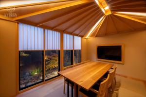 a dining room with a wooden table and windows at Kyoran Hayashi House, Aoumi - Vacation STAY 53463v in Gionmachi