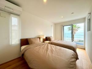 two beds in a bedroom with a view of the ocean at Shirahama Village - Vacation STAY 52778v in Minamiboso