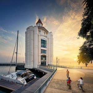 een groot wit gebouw met een boot in het water bij Marina Suite with Sunrise View in Tanjung Bungah