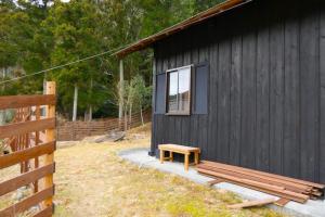a wooden bench next to a black building with a window at Camping-style accommodation: Yumeraku - Vacation STAY 65716v in Ema