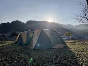 two tents in a field with the sun in the background at NATURE HEALING KAMIYAMA - Vacation STAY 71981v in Yorii