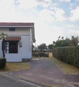 a white building with a driveway next to a hedge at Ryuyo Marine Park Auto Campsite - Vacation STAY 78095v in Kaketsuka