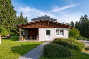 a small white house with a wooden roof at Ferienhaus Vier Jahreszeiten in Frauenwald