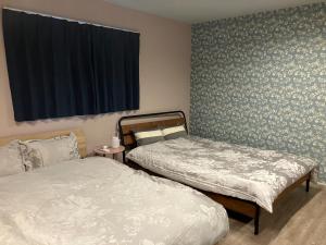 a bedroom with two beds and a window with a curtain at urumare - Vacation STAY 85310v in Teruma