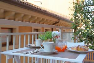 una mesa con platos de comida y bebida en el balcón en La Casetta di Lina Rooms and Apartments, en Verona