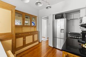 a kitchen with a stainless steel refrigerator and wooden cabinets at Fairlight 2-Bed Apartment Steps from the Beach in Sydney