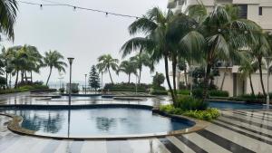 a pool in a resort with palm trees at Danga Bay Coastal Comfort 3BR 8Pax w 3Balcony by Our Stay in Johor Bahru