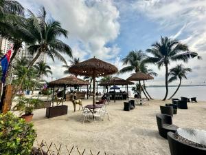 a beach with chairs and umbrellas and palm trees at Danga Bay Coastal Comfort 3BR 8Pax w 3Balcony by Our Stay in Johor Bahru