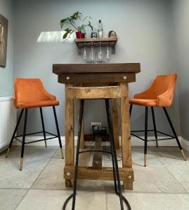a wooden table with two orange bar stools at Globe Cottage in Glastonbury