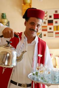 a man is holding a tea kettle on a tray at Iberostar Selection Royal El Mansour in Mahdia
