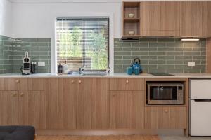a kitchen with wooden cabinets and a microwave at Nordhaus Studio in Smiths Lake +11 photos