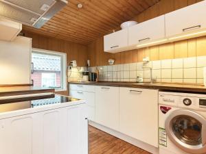 a kitchen with white cabinets and a washer and dryer at 4 person holiday home in Martofte-By Traum in Nordskov