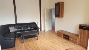 a living room with a black leather couch and a table at Boardinghaus Niederrhein in Viersen