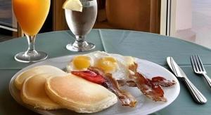 Un plato de desayuno con huevos, tocino y panqueques. en Shalimar Hostel, en Las Vegas