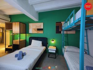 two beds in a room with a green wall at Citizen Hotel in Manila