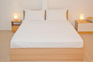 a bed with white sheets and two lamps on tables at Singah in Bukit Mertajam