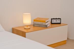 a bedside table with a clock and books on it at Singah in Bukit Mertajam