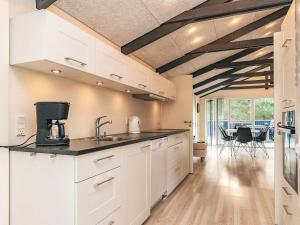 a kitchen with white cabinets and a table with chairs at 4 star holiday home in Hals in Hals