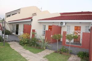 a white and red house with a red fence at Flamboyant Guest Lodge in Johannesburg