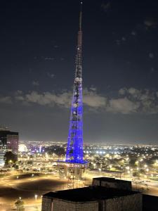 a tall tower lit up in blue at night at Nobile Suites, Flats Rocha in Brasília