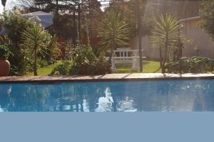 a swimming pool with a bench in a garden at Flamboyant Guest Lodge in Johannesburg