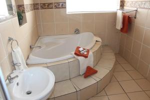 a bathroom with a tub and a toilet and a sink at Flamboyant Guest Lodge in Johannesburg +19 photos