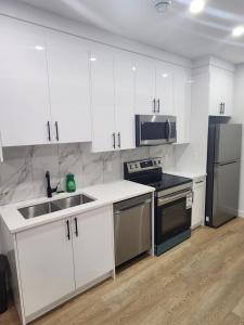 une cuisine avec des armoires blanches, un évier et un réfrigérateur dans l'établissement Home in Calgary, à Calgary