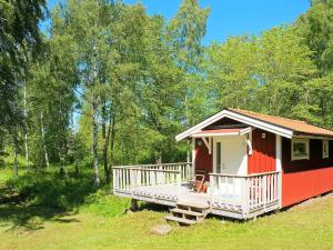 a red and white cabin in a field with trees at 4 person holiday home in AXVALL in Axvall +10 photos